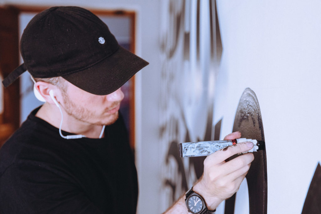 Miguel Spínola painting calligraphy "Breakthrough" on KOBU agency's wall