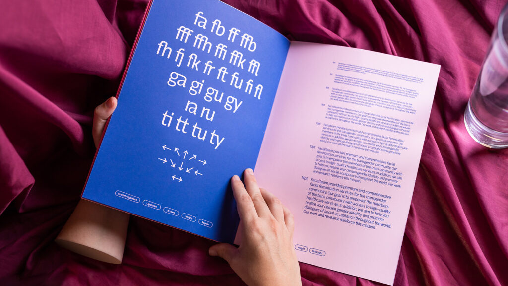 A hand opening a type specimen of Facialteam's custom typeface "FT Text", designed by KOBU Agency