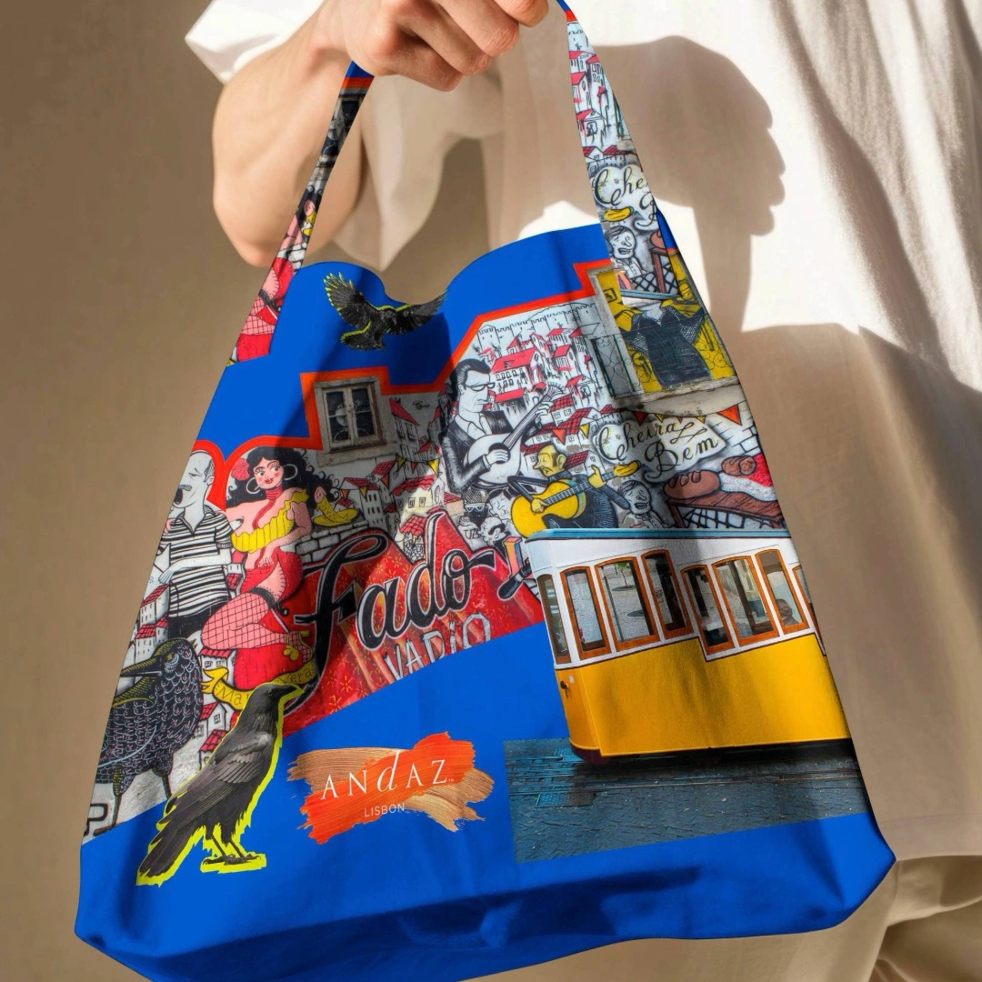 Person holding a colorful Andaz Lisbon tote bag featuring Lisbon-inspired illustrations and a yellow tram