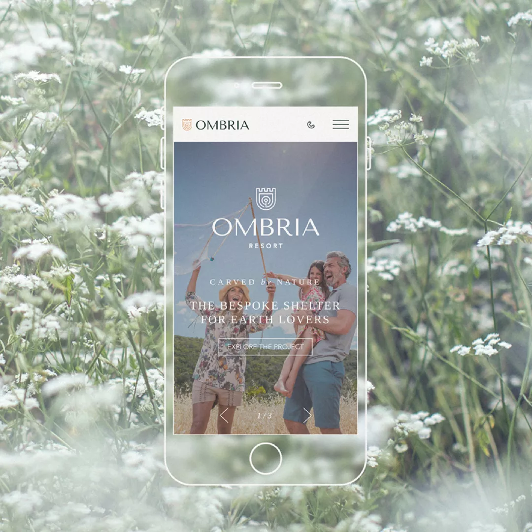 Smartphone displaying Ombria website with family outdoors and tagline 'Carved by Nature'