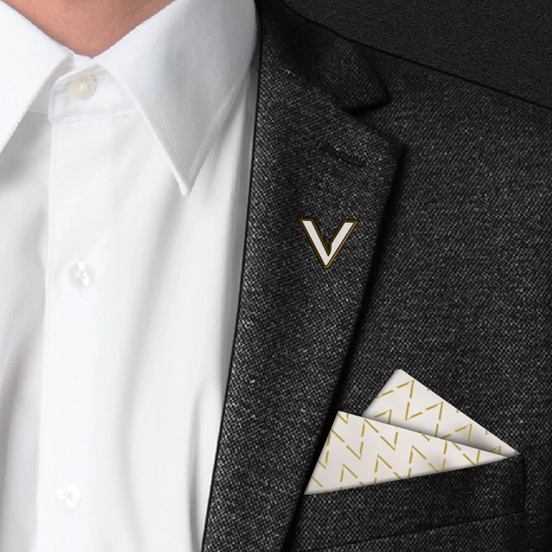 Man wearing dark suit jacket with gold TheV Apartments pin and branded pocket square