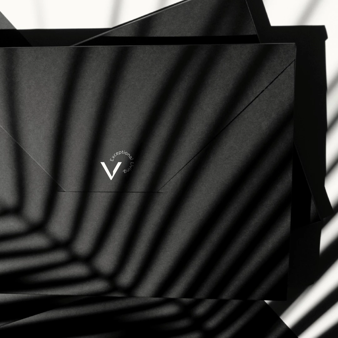 Black envelope with TheV Apartments logo partially illuminated by shadow patterns