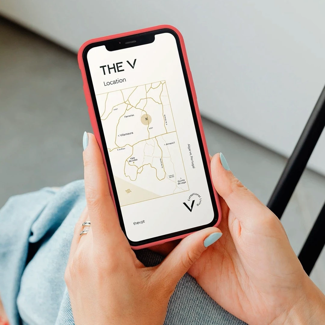 Hands holding smartphone showing TheV Apartments location map on screen